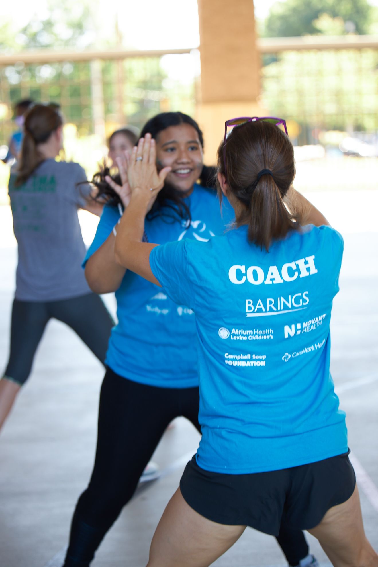 Two girls in Girls on the Run shirts embrace with smiles